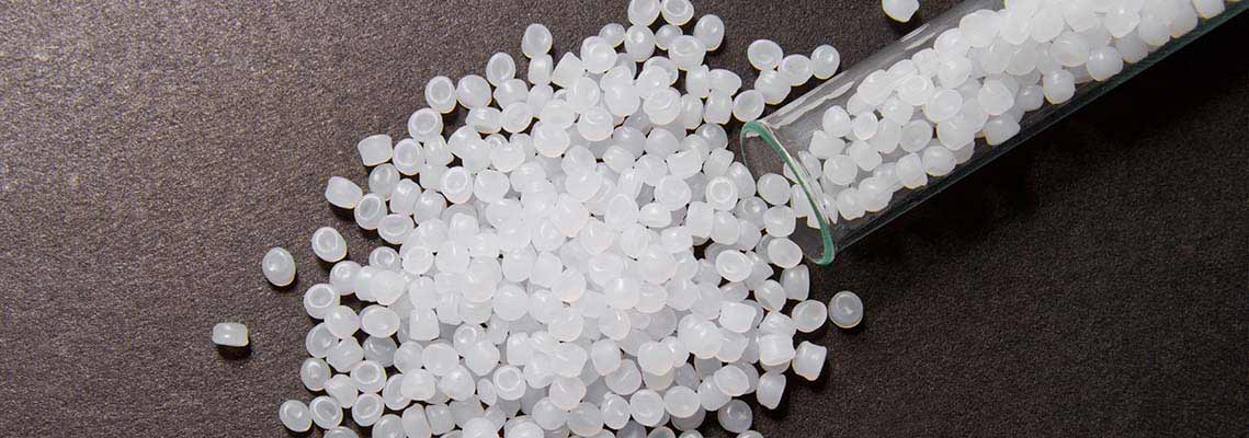 Polyethylene granules in a test tube, milky-transparent on a black background